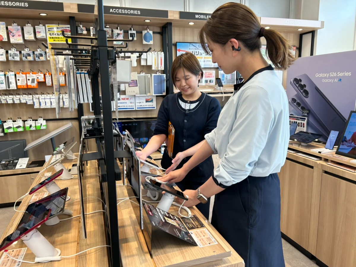 スマートフォンのデモ機を拭いて開店準備をするスタッフ