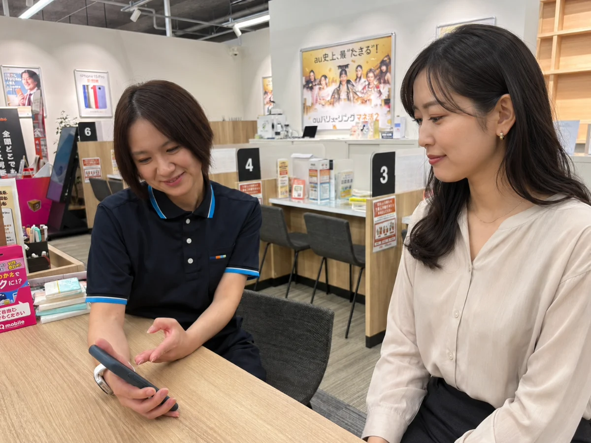 お客様にスマホ画面を見せながら操作を教えるスタッフ
